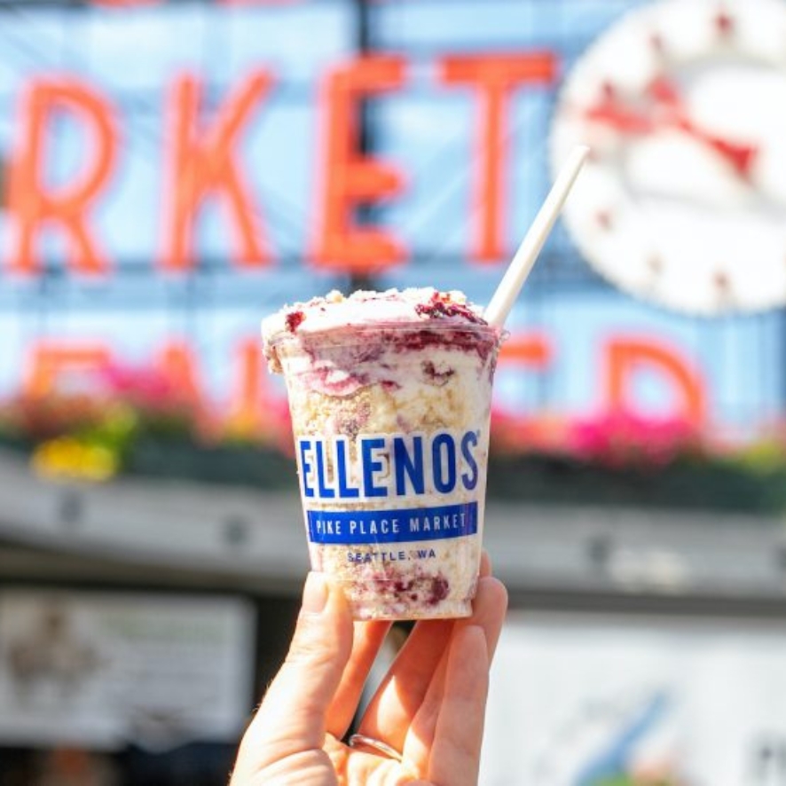 A hand holding a cup of Ellenos Greek Yogurt at Pike Place Market in Seattle